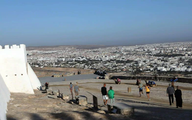 Agadir cityscape view from hilltop with tourists exploring historic site.