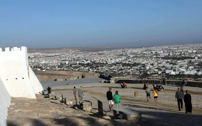 Agadir cityscape view from hilltop with tourists exploring historic site.