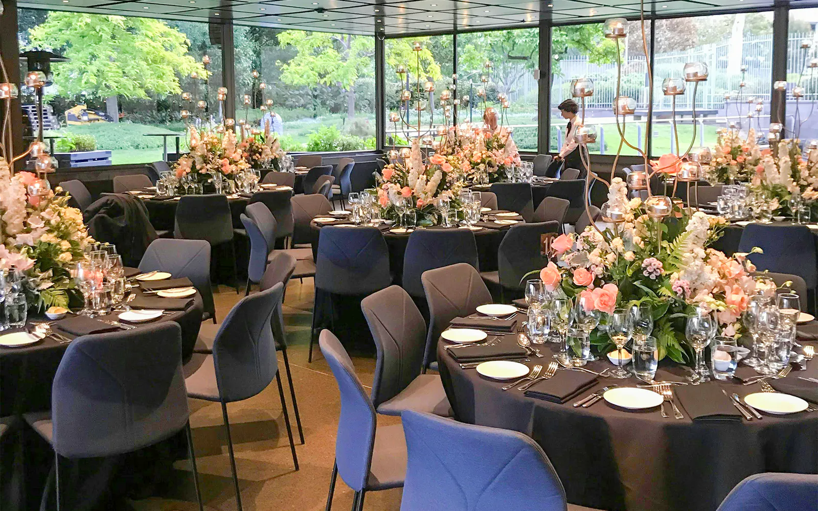 NGV garden restaurant interior with tables set and floral decorations.