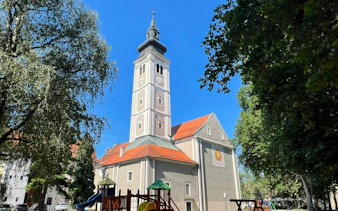 Cathedral of the Assumption of the Virgin Mary tower in Varaždin, Croatia, surrounded by trees.