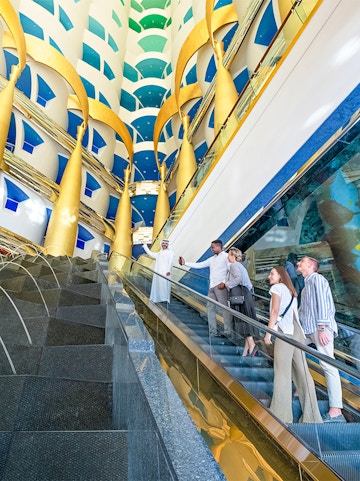 Visitors on an escalator inside Burj Al Arab, admiring the luxurious interior design.