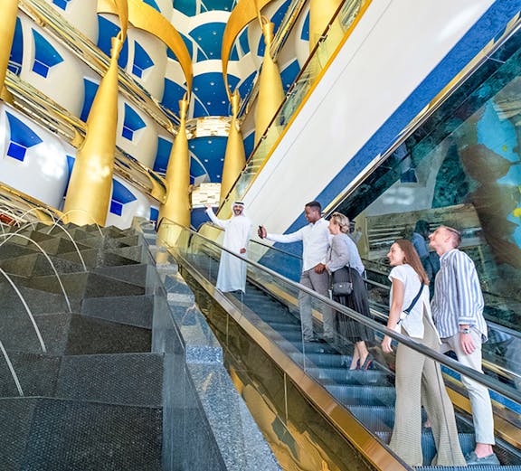 Visitors on an escalator inside Burj Al Arab, admiring the luxurious interior design.