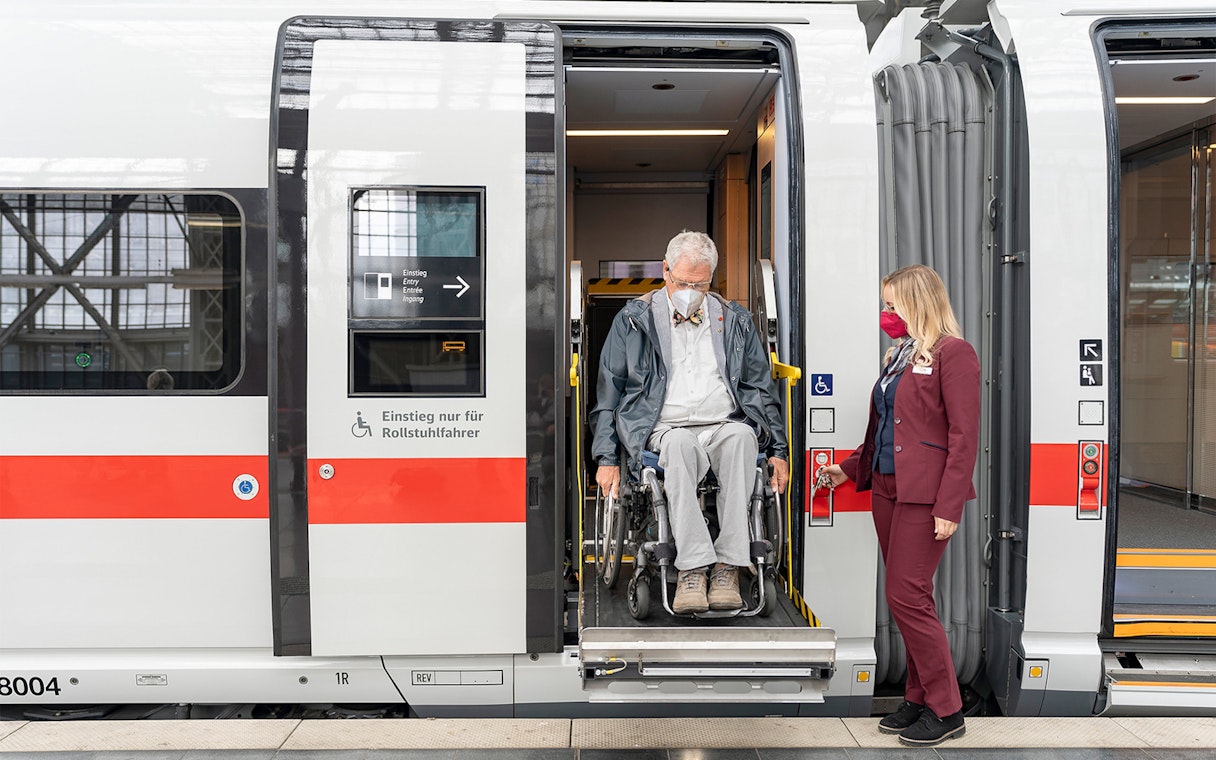 Man in wheelchair exiting train with assistance in Germany.