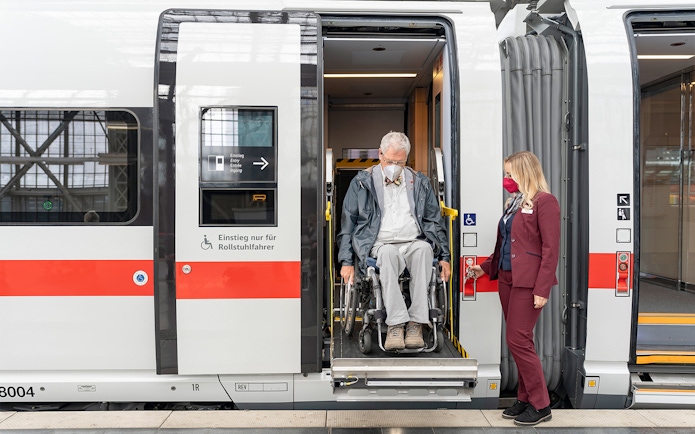 Man in wheelchair exiting train with assistance in Germany.
