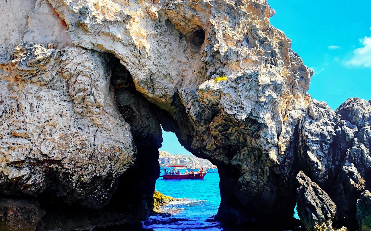 Ferry passing through rocky archway on Vieste to Tremiti Islands route.