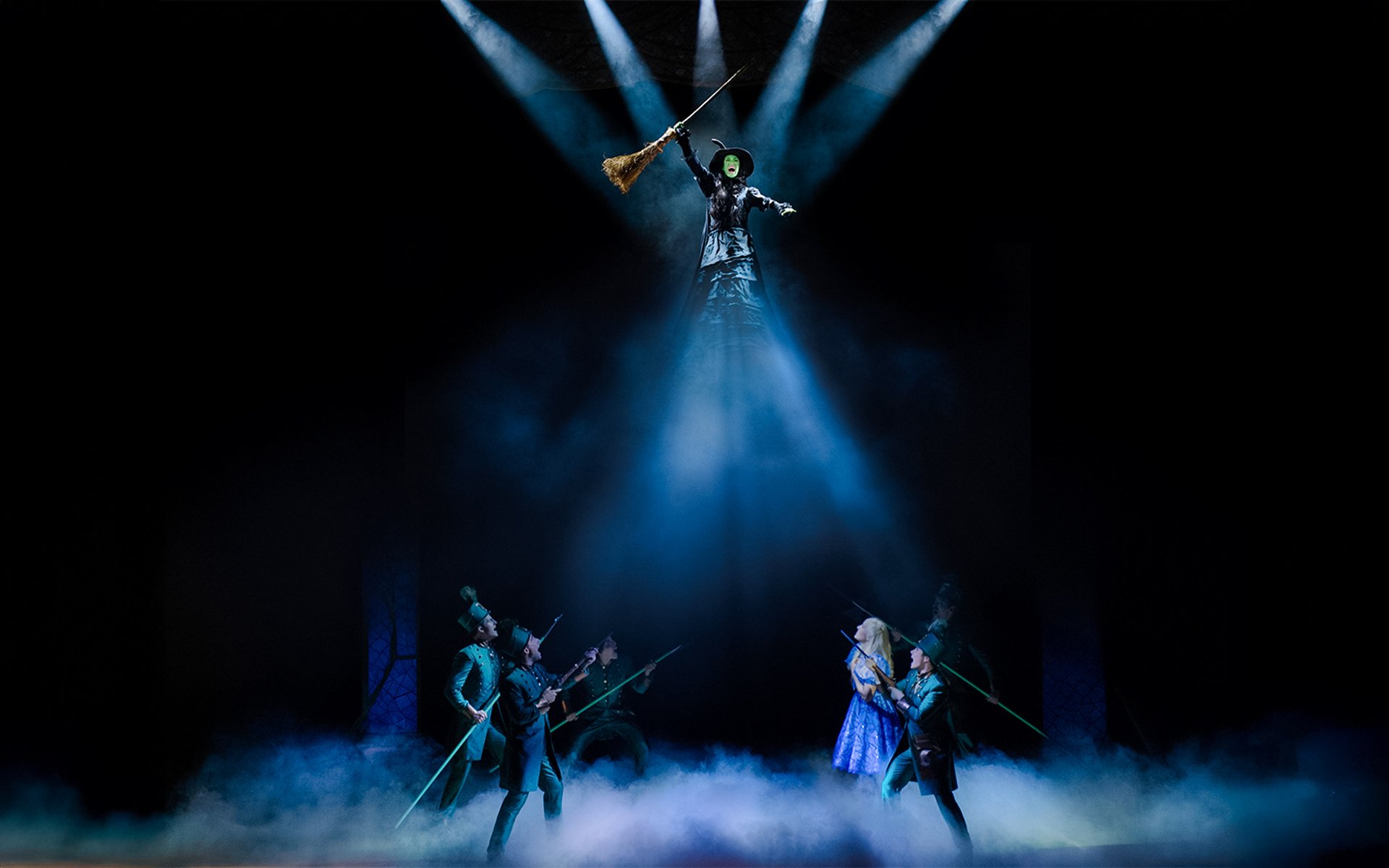 Wicked stage performance with actors in Madrid, featuring a witch flying on a broom.