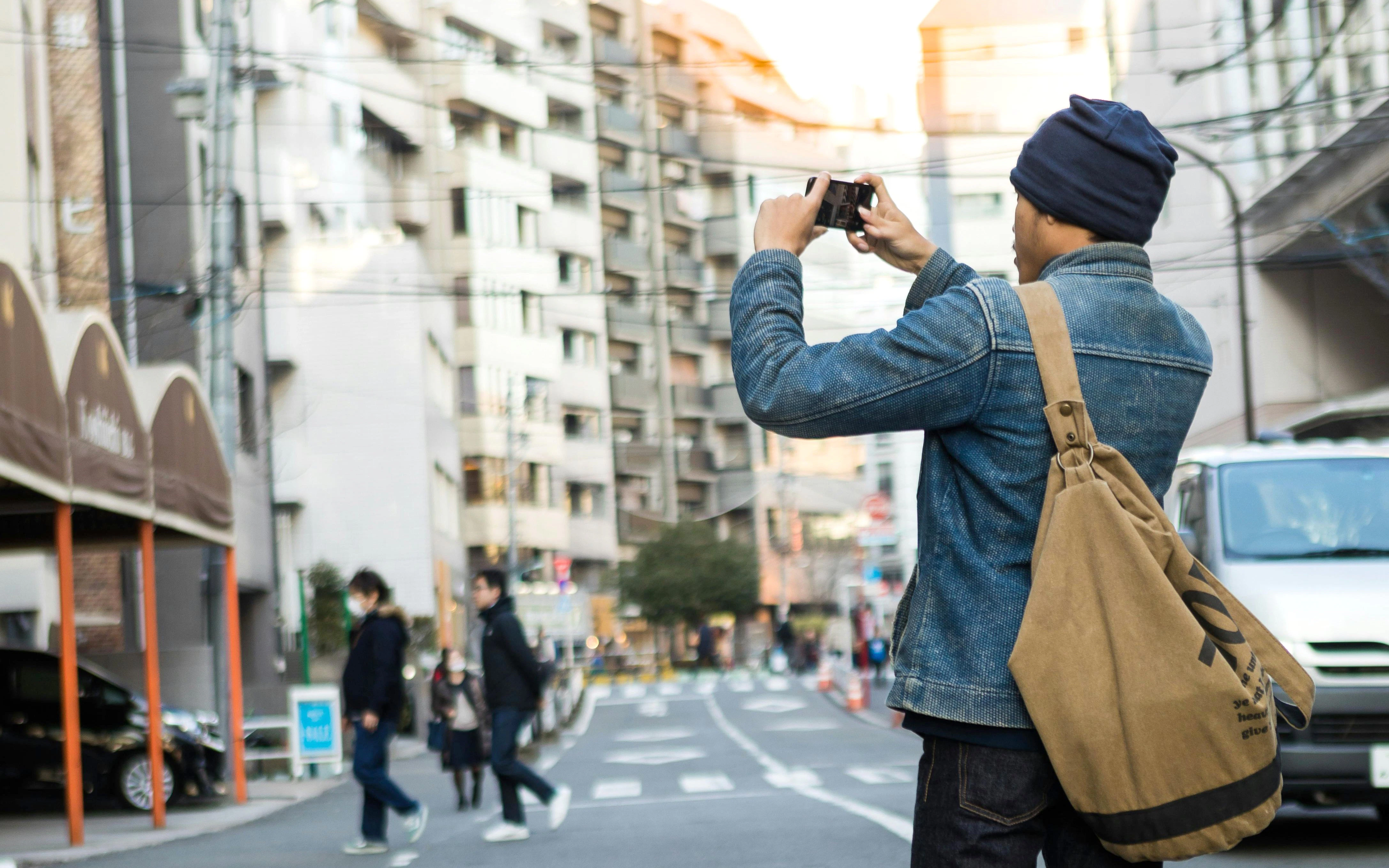 Asian man photographing street scene in Shibuya, Tokyo, Japan.