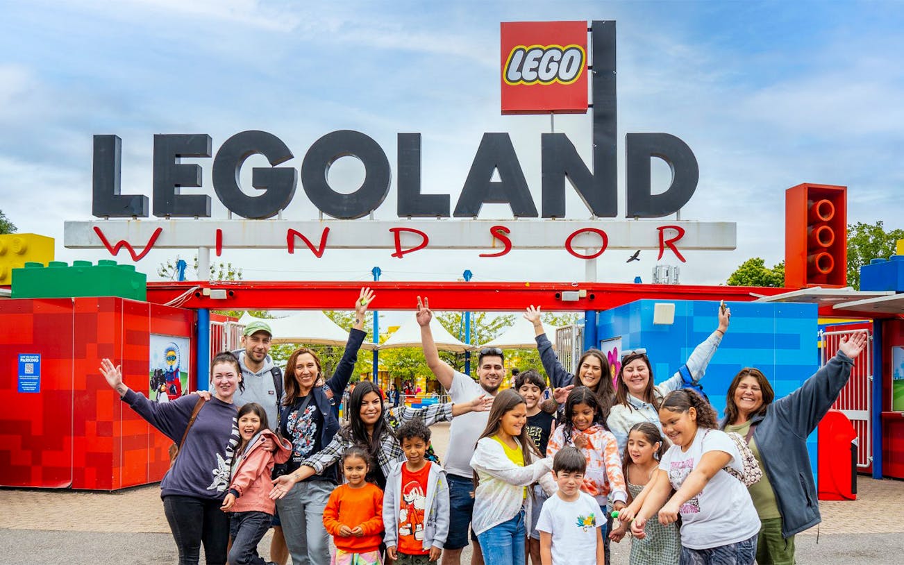 Visitors at the entrance of Legoland Windsor with the iconic sign overhead.