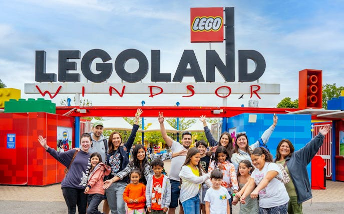 Visitors at the entrance of Legoland Windsor with the iconic sign overhead.