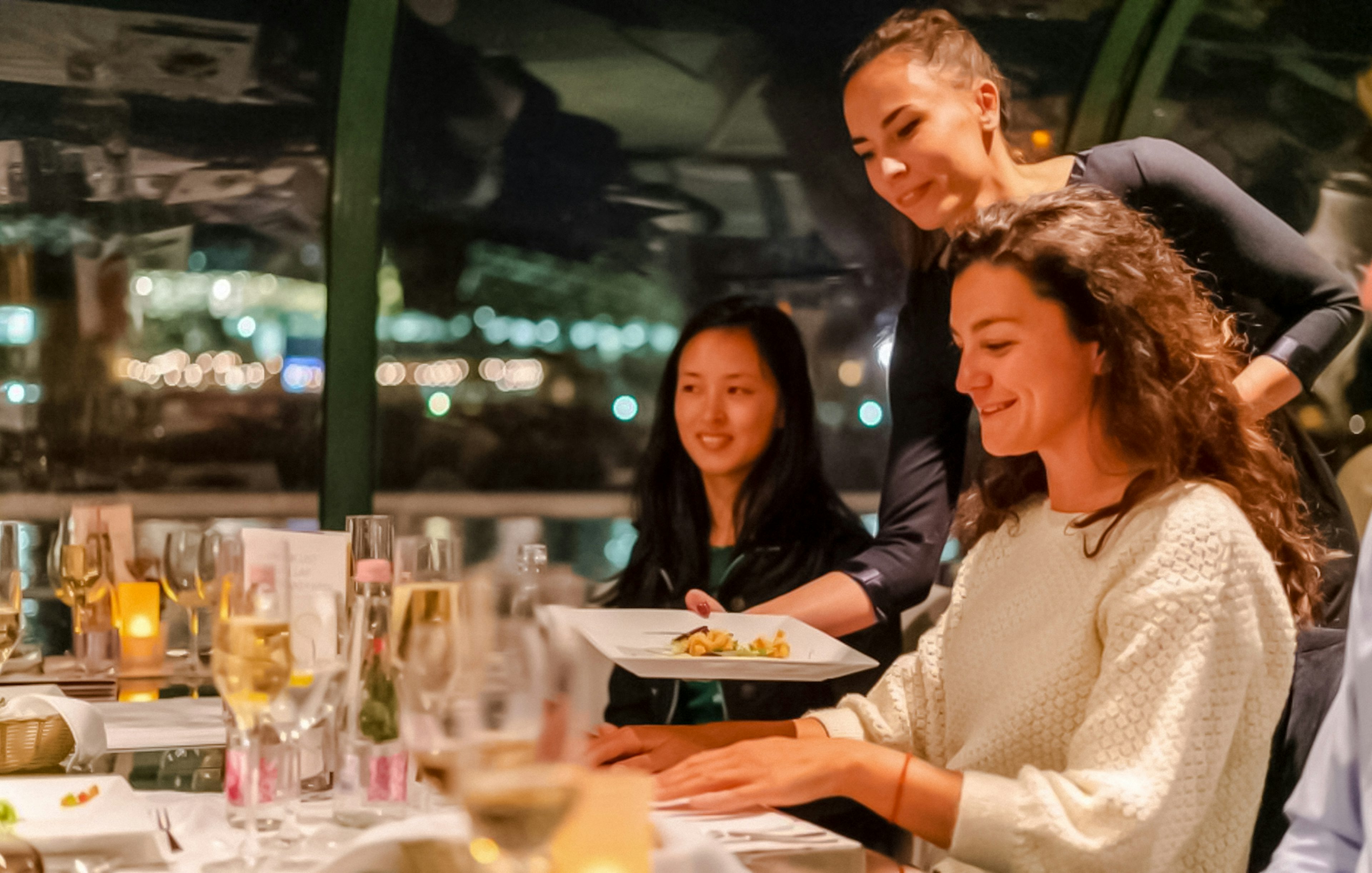 Server presenting dish during Budapest Danube River candlelit dinner cruise.