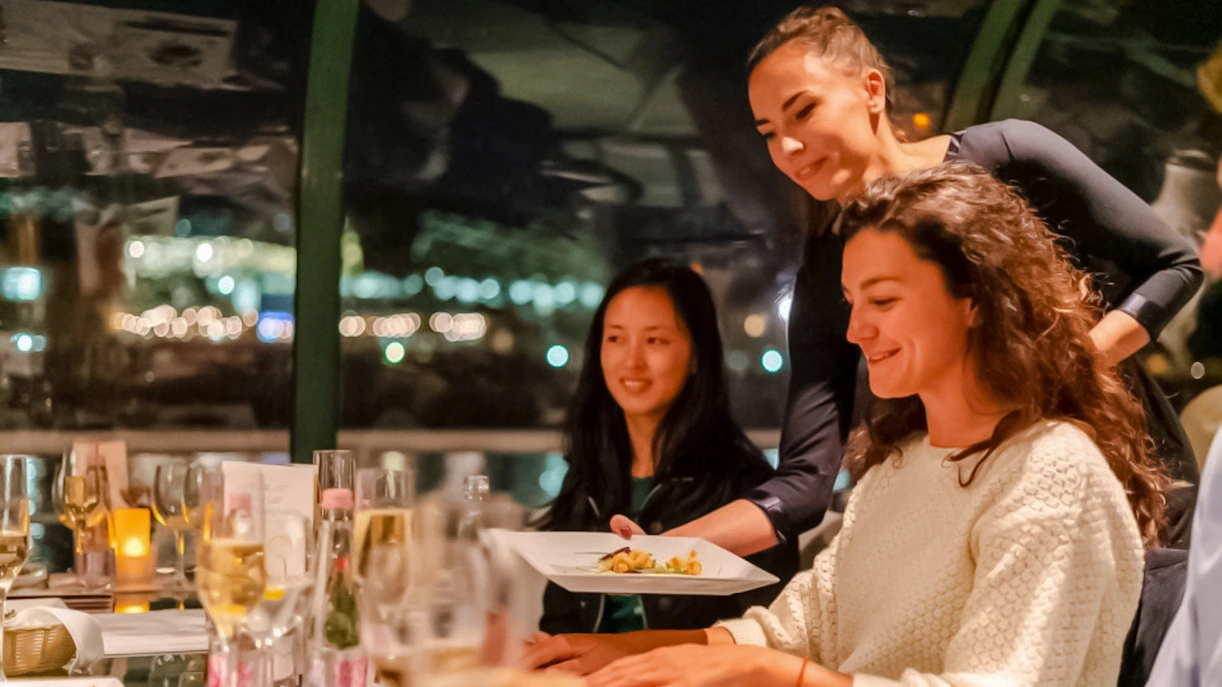 Server presenting dish during Budapest Danube River candlelit dinner cruise.