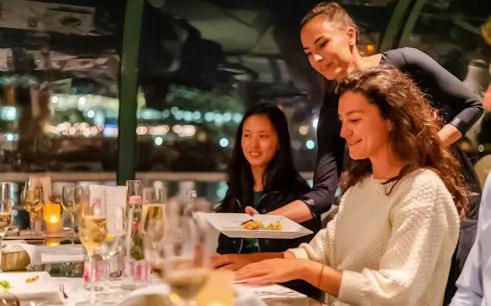 Server presenting dish during Budapest Danube River candlelit dinner cruise.
