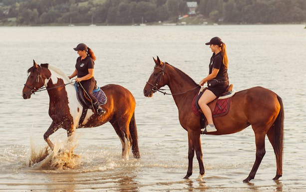 Horseback riding by a lake near Krakow, featuring two riders in the water.