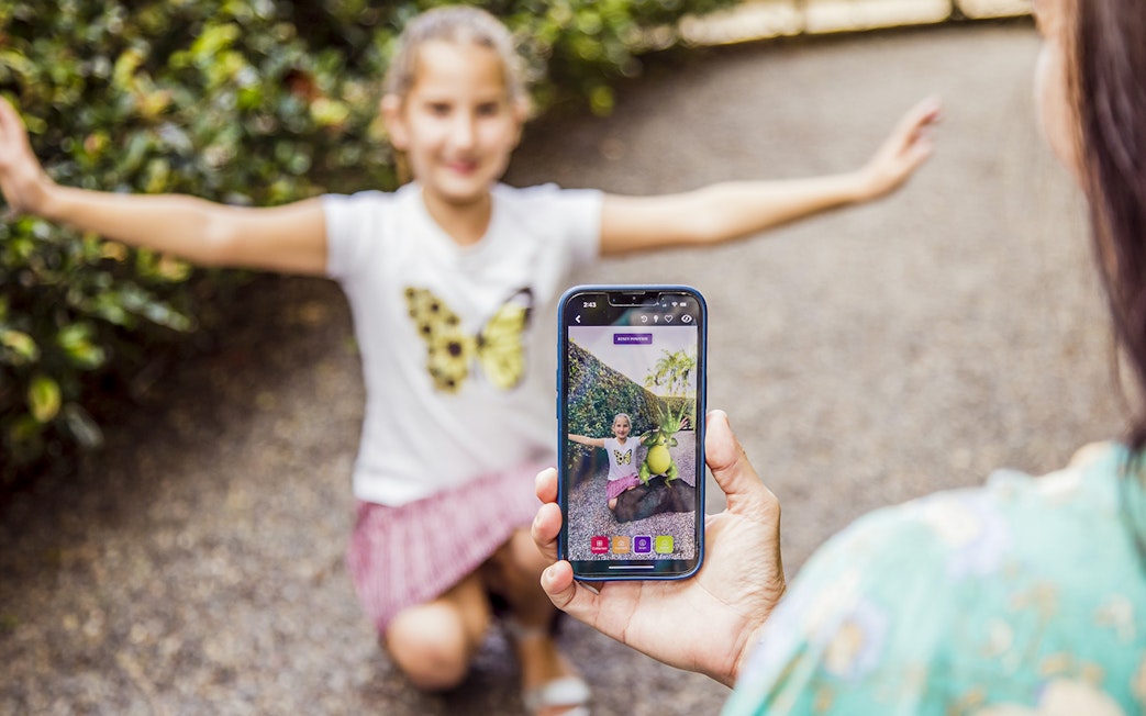 Child posing with arms outstretched at Amaze World, captured on a smartphone.