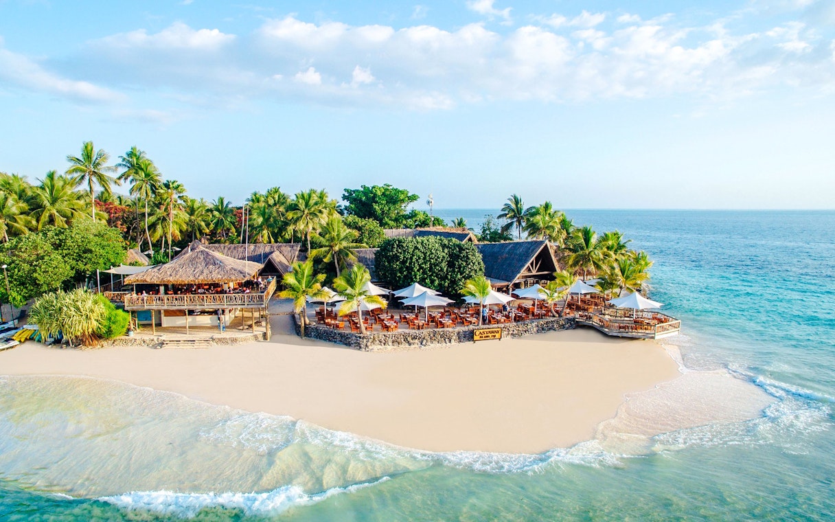 Aerial view of beachfront resort on Castaway Island, Fiji with palm trees and ocean.