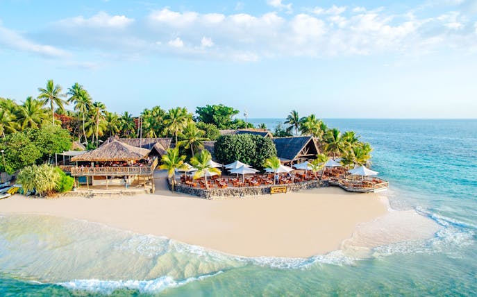 Aerial view of beachfront resort on Castaway Island, Fiji with palm trees and ocean.