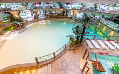 Indoor wave pool at Club D Oasis, surrounded by palm trees and LED screen.