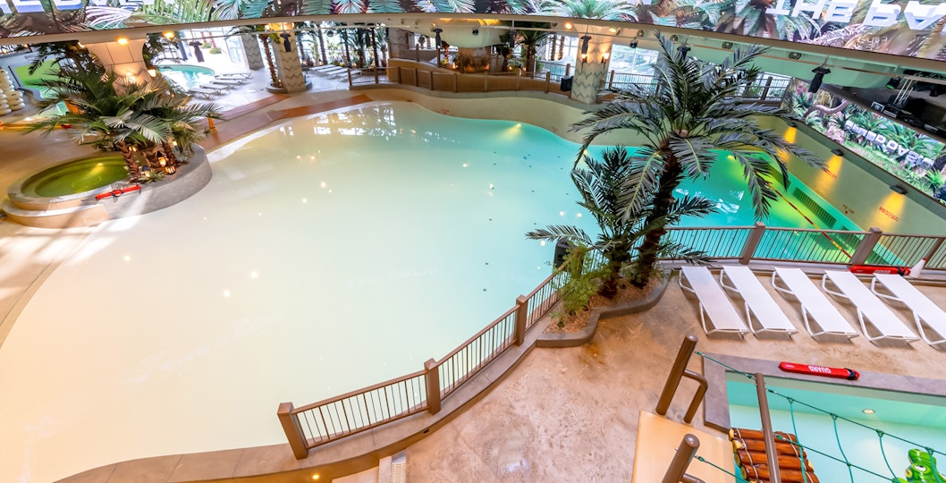 Indoor wave pool at Club D Oasis, surrounded by palm trees and LED screen.