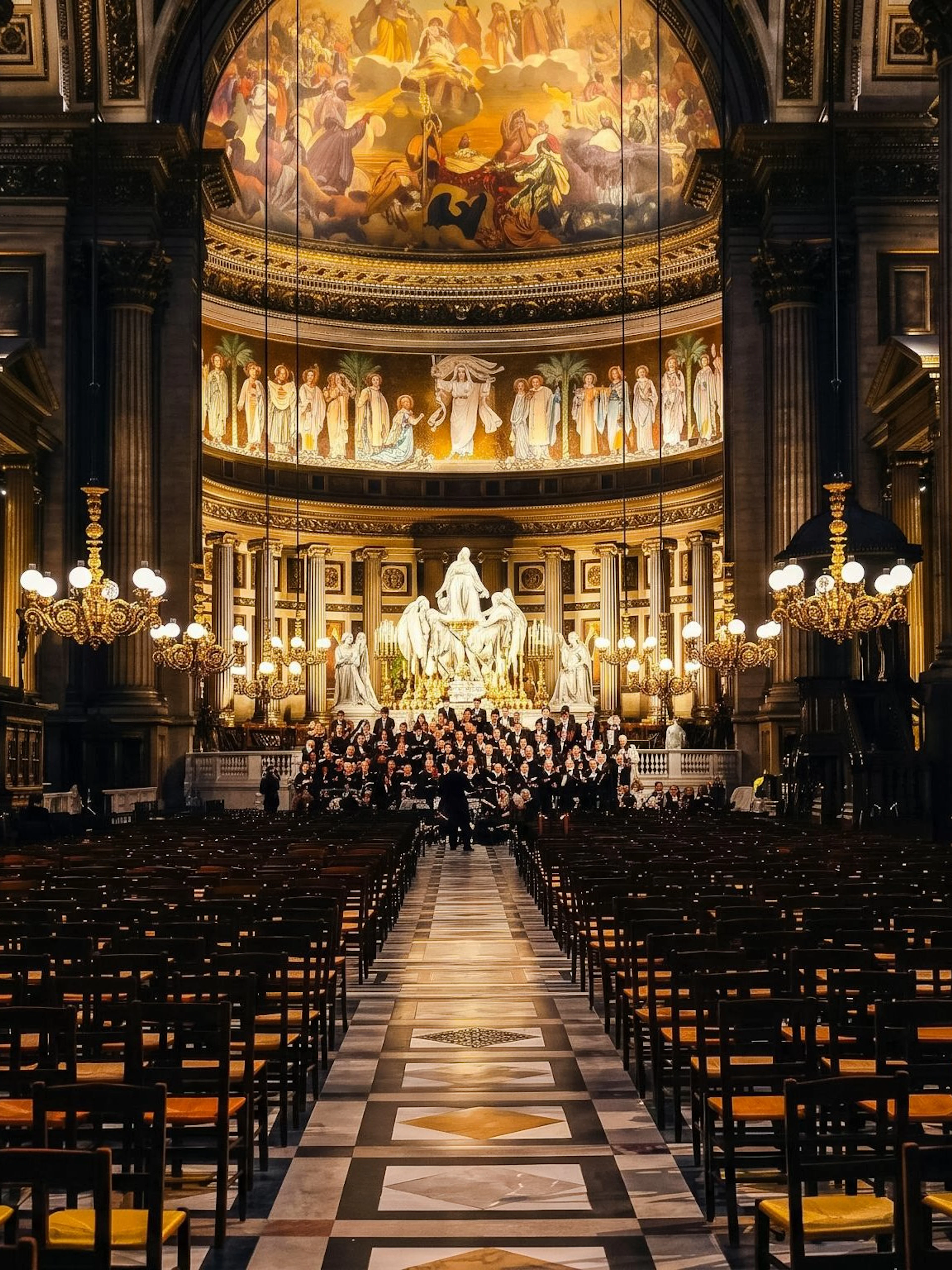 Orchestra Hélios performing in Église de la Madeleine, Paris, with ornate chandeliers and frescoes.