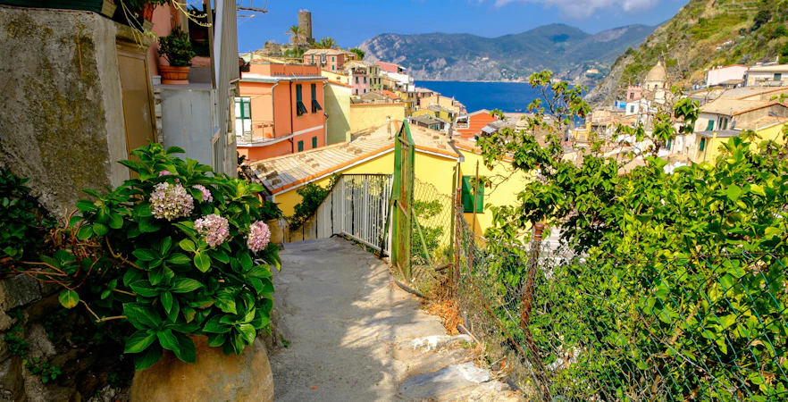 Hiking path view between Corniglia and Vernazza, Cinque Terre, with colorful houses and sea.