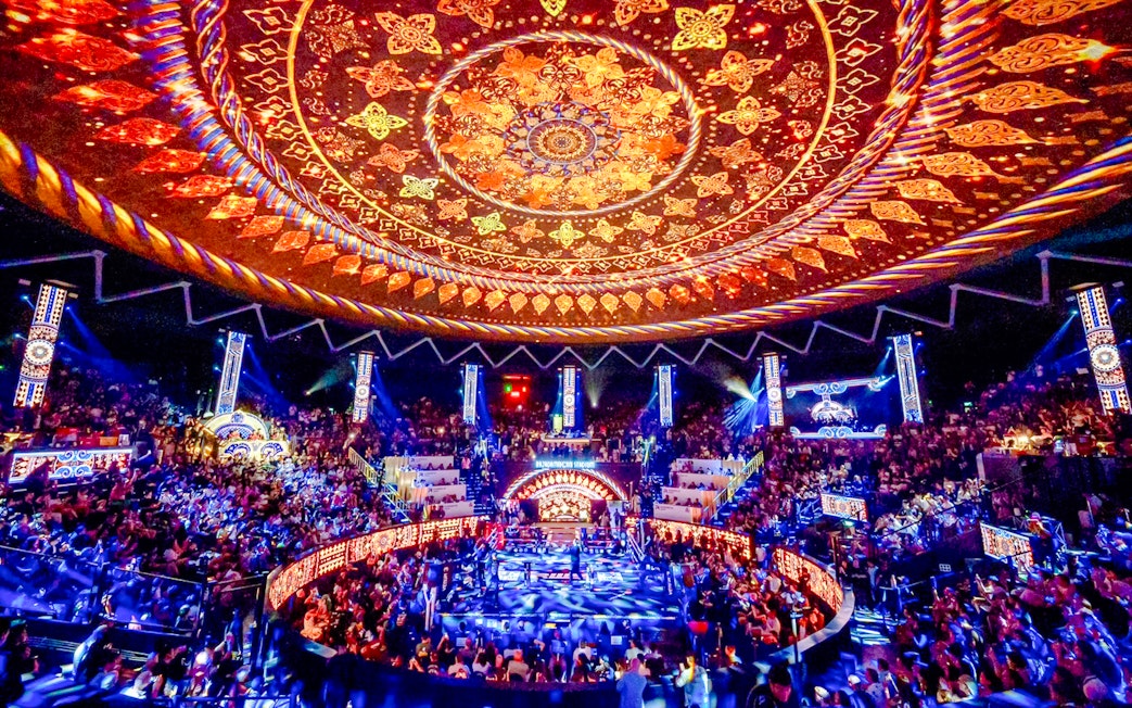 Rajadamnern Boxing Stadium interior with ornate ceiling and vibrant crowd.