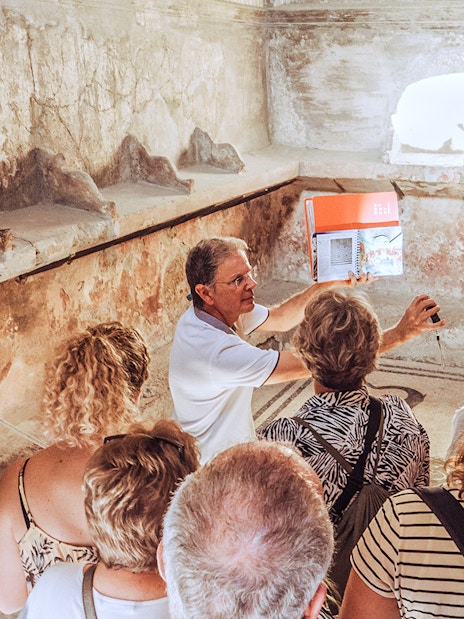 Guide explaining ancient ruins to a group of tourists in Pompeii, Italy.