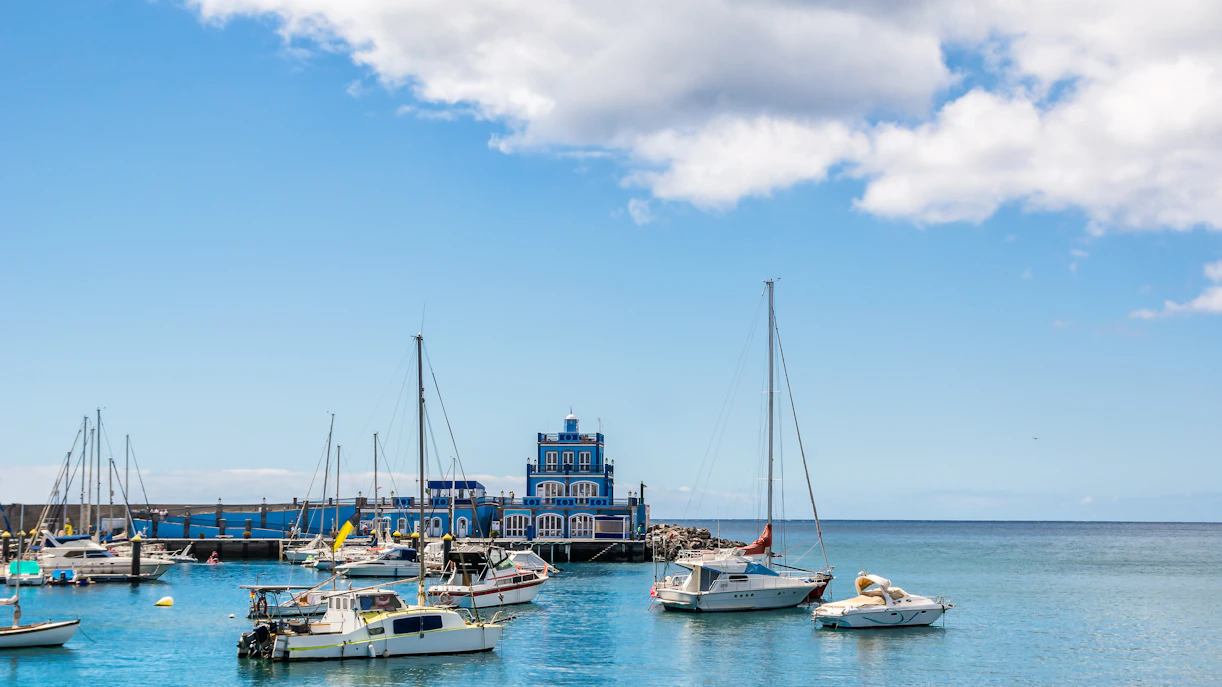 Boats in Marina del Sur with blue harbormaster house, Las Galletas, Tenerife, Spain.