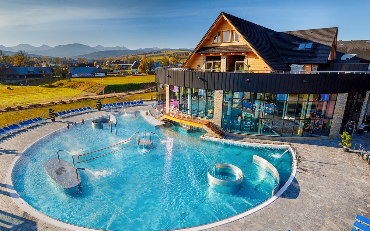 Aerial view of Chocholow Thermal Baths with outdoor pool and mountain backdrop.
