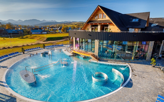 Aerial view of Chocholow Thermal Baths with outdoor pool and mountain backdrop.