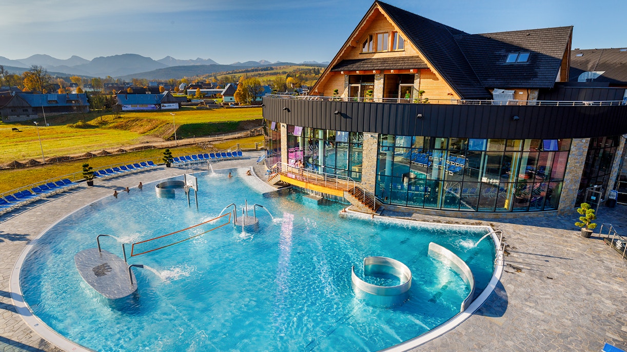 Aerial view of Chocholow Thermal Baths with outdoor pool and mountain backdrop.