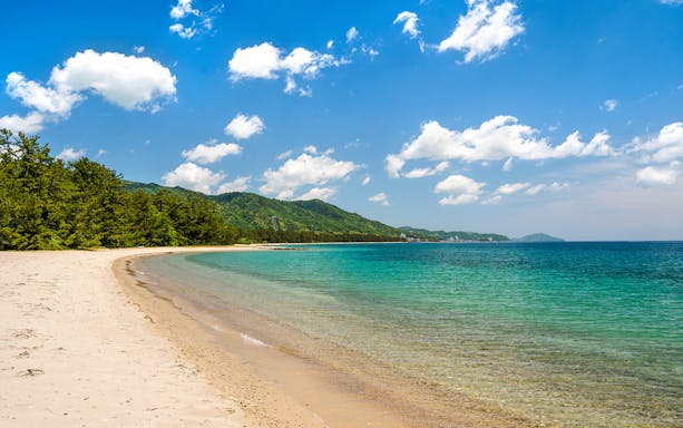 Amanohashidate white sand beach with clear blue water and lush green hills on Kyoto Coastal Tour.