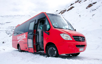 Red tour bus in snowy Valle Nevado, Santiago, ready for excursion.