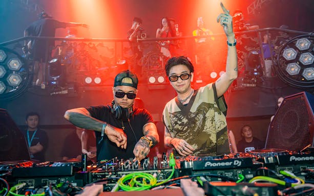 DJs performing at Atlas Super Night Club with vibrant lighting and crowd in the background.