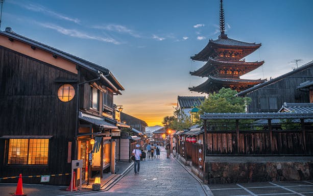 Street view of Kyoto's historic district with Yasaka Pagoda at sunset.