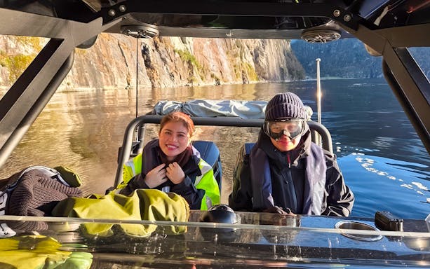 Guests on a RIB boat enjoying Alversund Fjord Safari with rocky cliffs in the background.