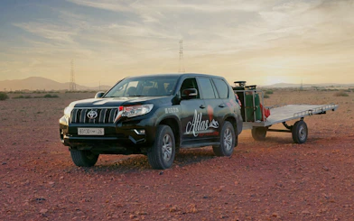 SUV with trailer on desert terrain at sunrise in Marrakech.