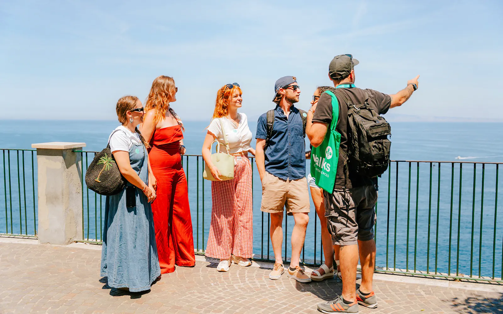 Tour group enjoying Amalfi Coast views with guide pointing at the sea.
