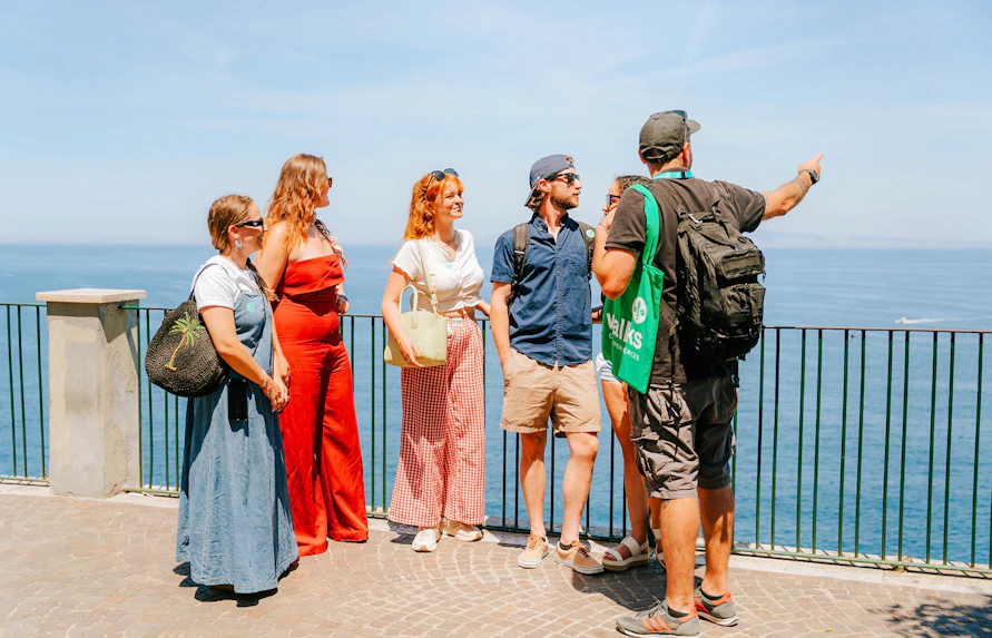 Tour group enjoying Amalfi Coast views with guide pointing at the sea.