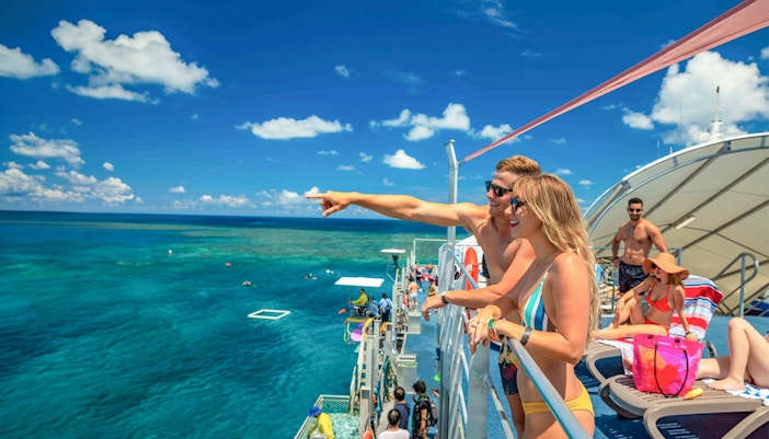Tourists snorkeling at Fitzroy Island with Great Barrier Reef in view.