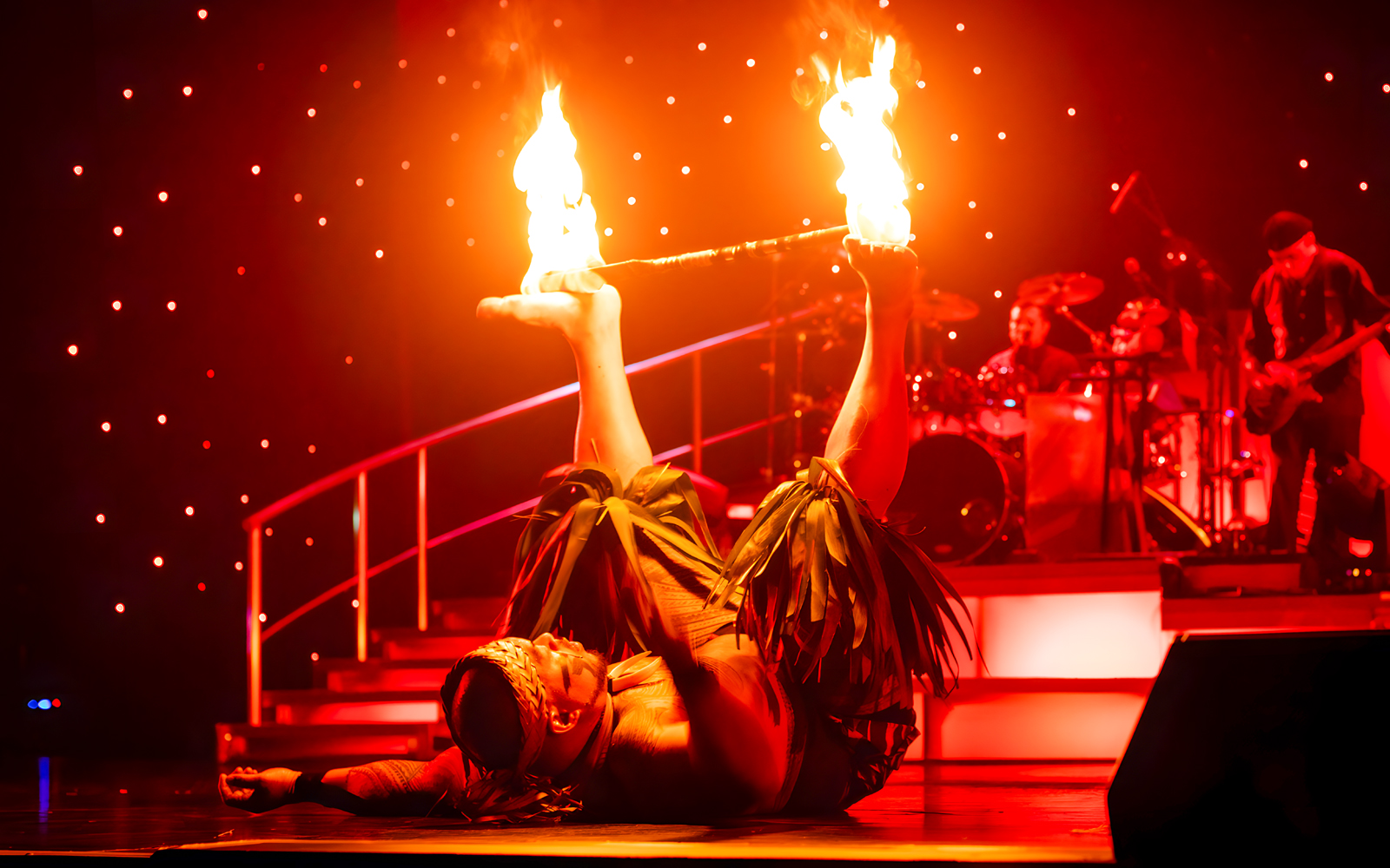 Fire dancer performing with flaming sticks on stage at Rock-A-Hula show.