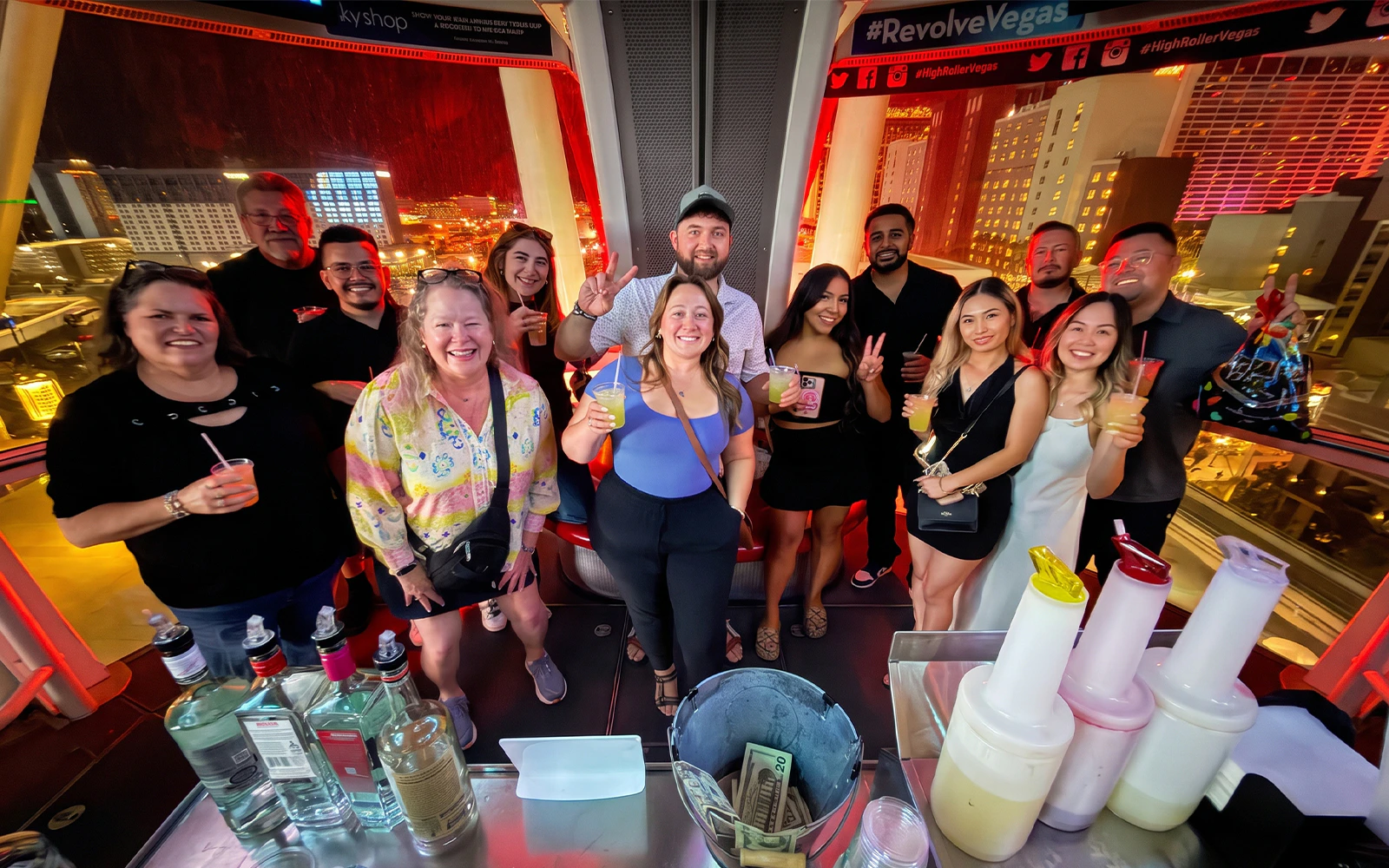 Guests enjoying drinks inside the High Roller gondola with a view of Las Vegas at night.