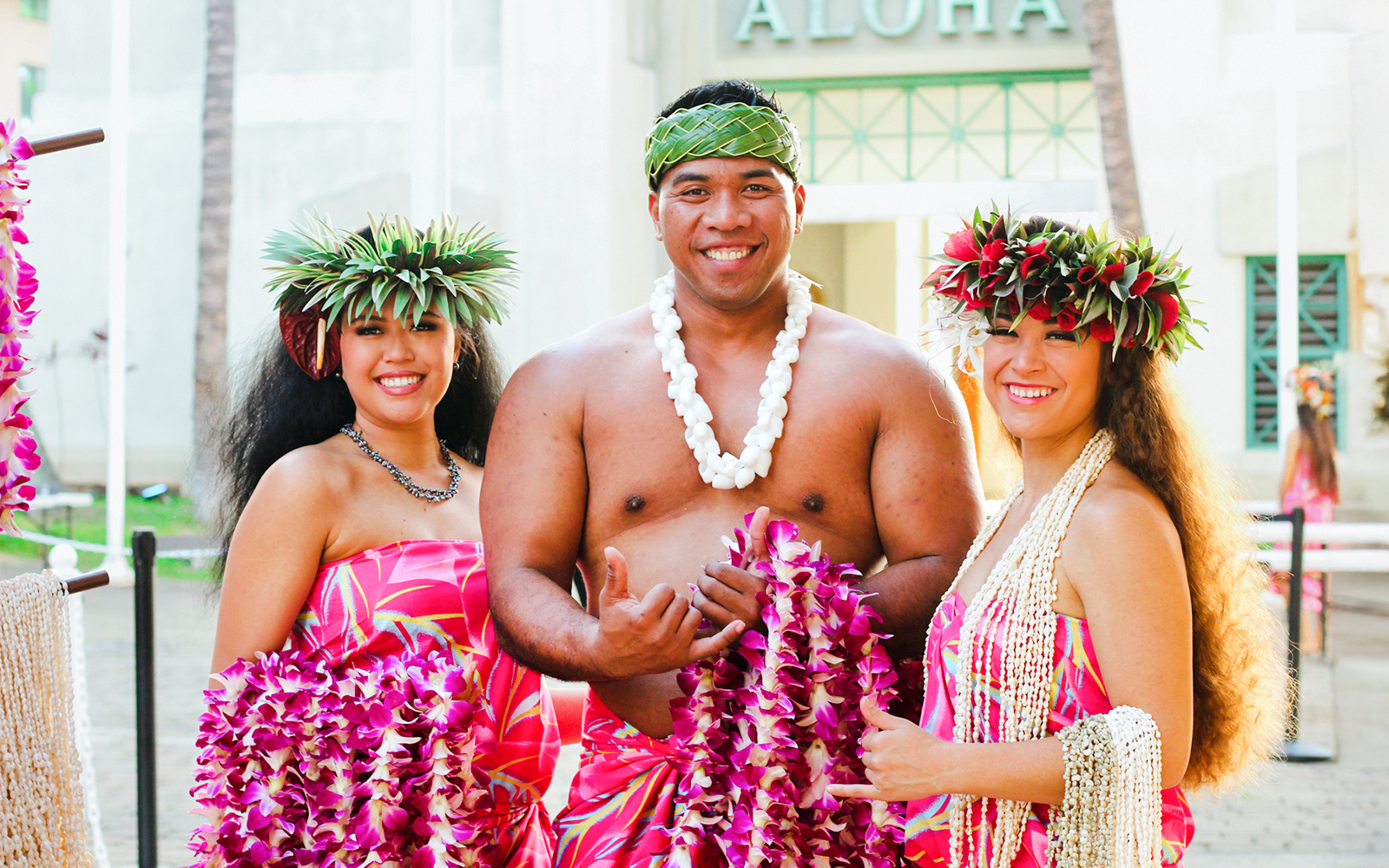 Performers in traditional attire at Moana Luau, Hawaii, holding flower leis.