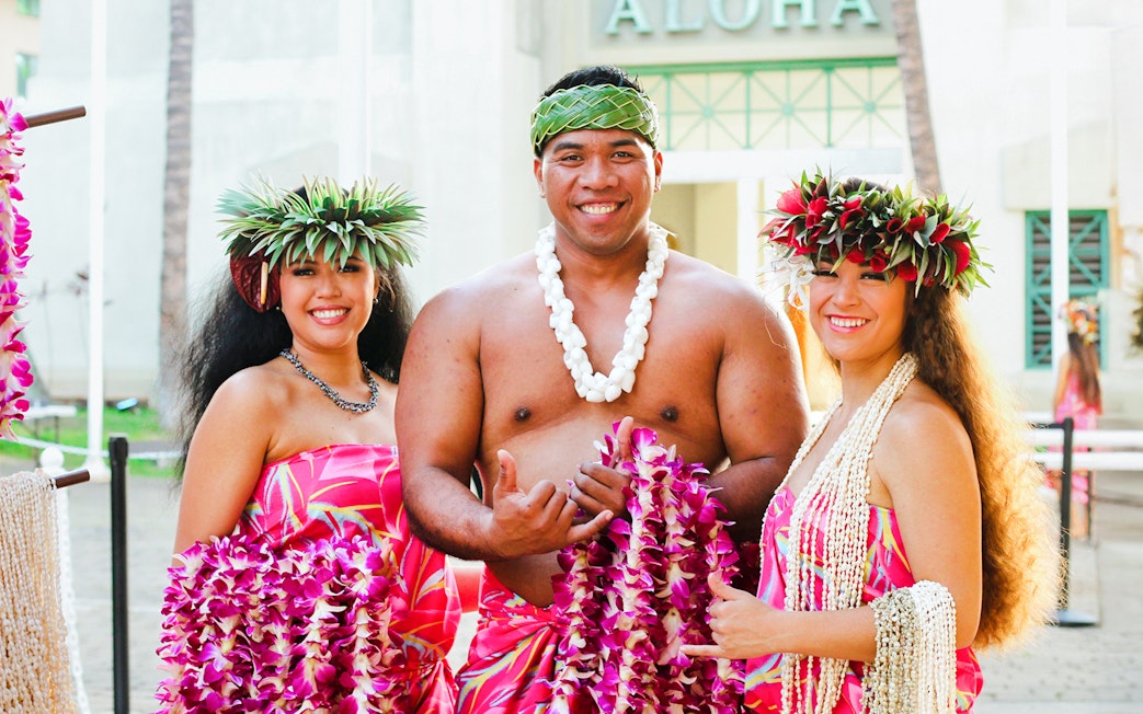 Performers in traditional attire at Moana Luau, Hawaii, holding flower leis.