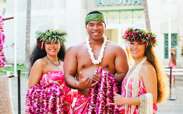 Performers in traditional attire at Moana Luau, Hawaii, holding flower leis.