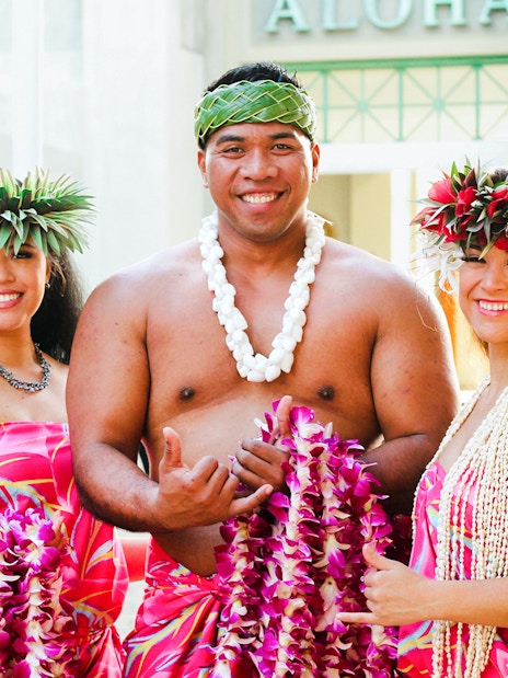 Performers in traditional attire at Moana Luau, Hawaii, holding flower leis.