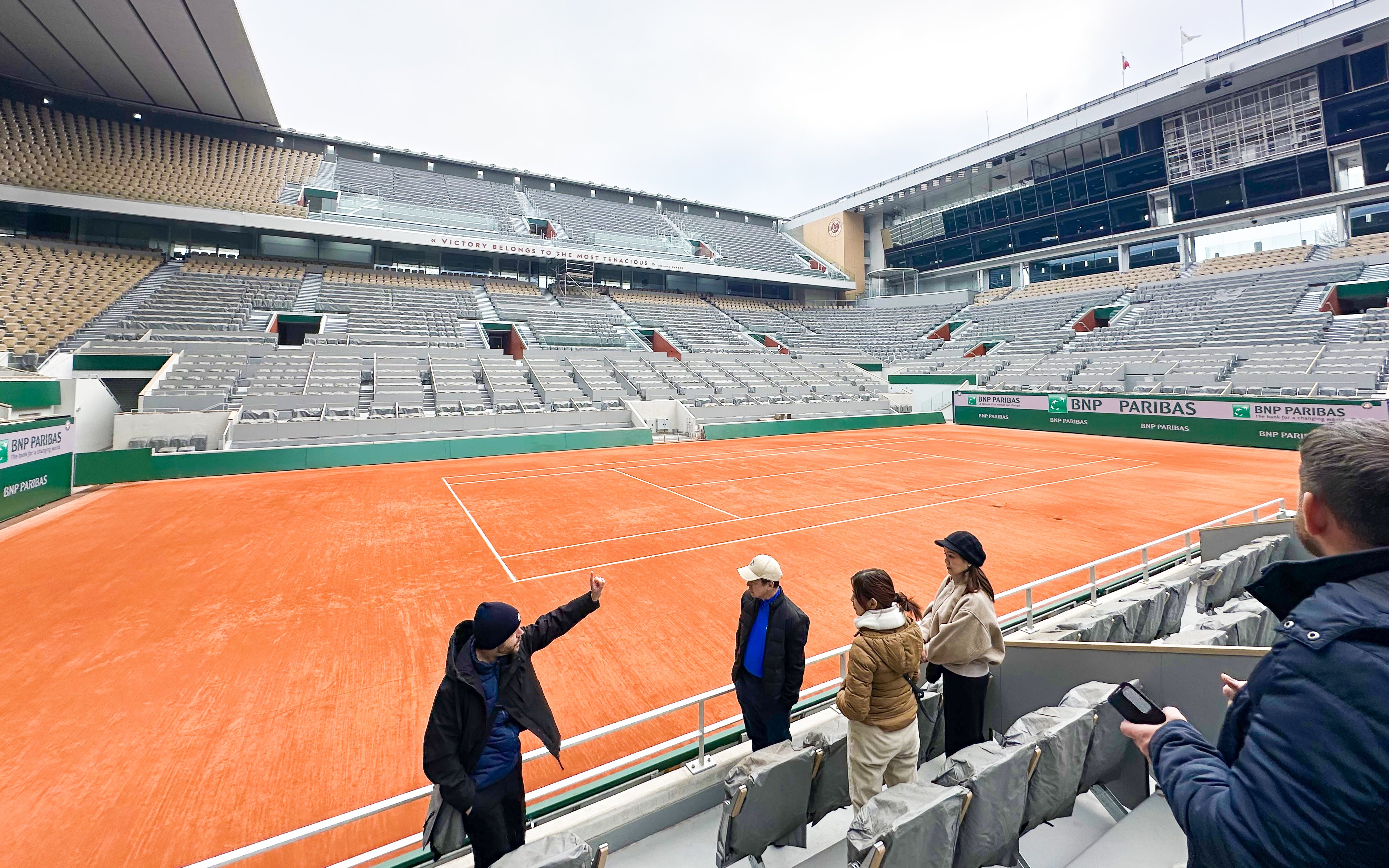 Tour group at Roland-Garros Stadium overlooking the clay tennis court.