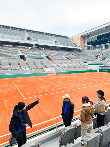 Tour group at Roland-Garros Stadium overlooking the clay tennis court.