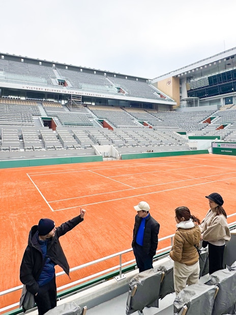 Tour group at Roland-Garros Stadium overlooking the clay tennis court.