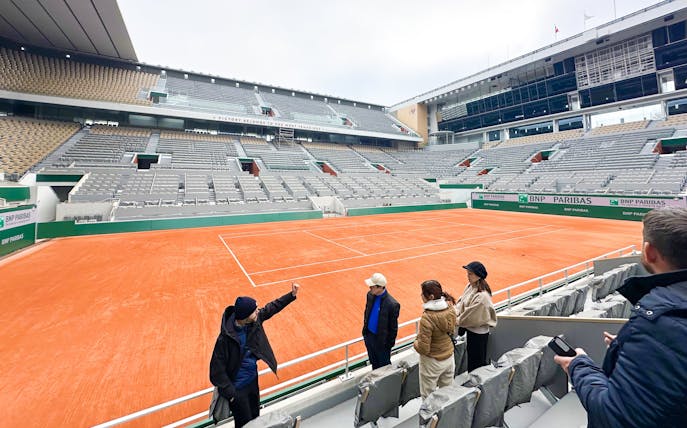 Tour group at Roland-Garros Stadium overlooking the clay tennis court.
