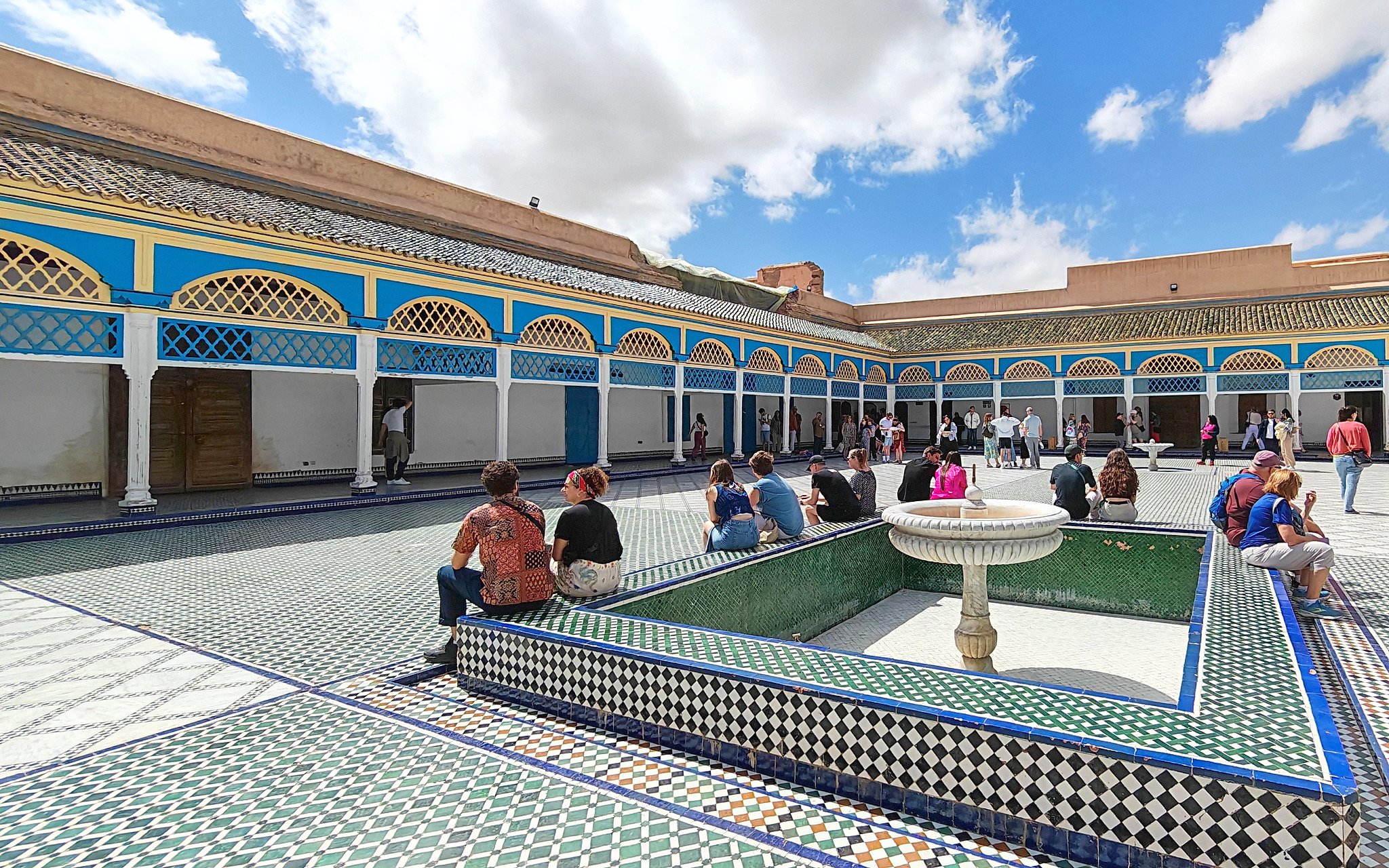 Bahia Palace courtyard with visitors seated around a fountain, Marrakech.